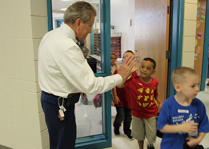 Superintendent gives high five to kindergarten student in red shirt