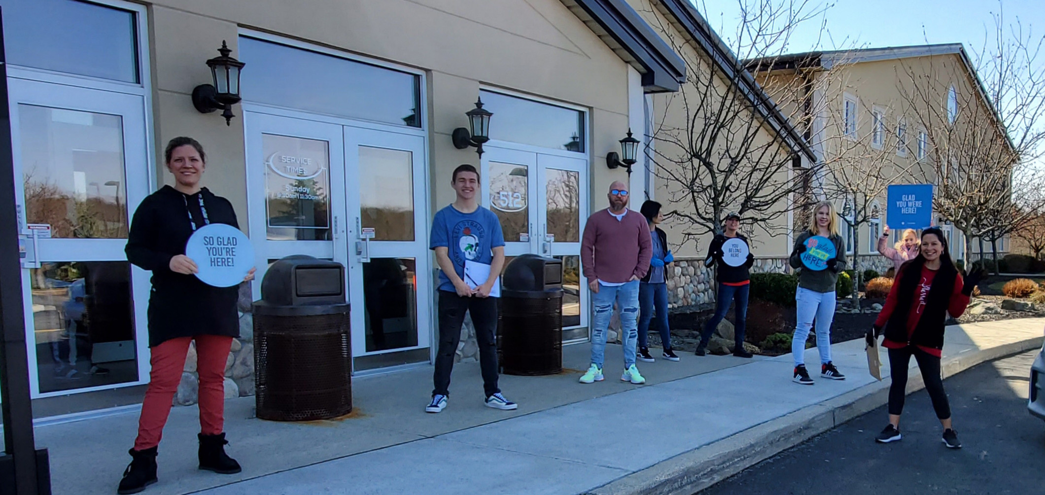 Seven people stand in front of a brick building