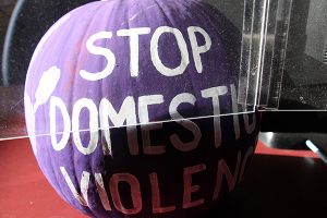 A pumpkin is painted purple with the words Stop Domestic Violence written in white.