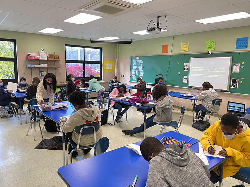 A class of sixth-grade students are at individual desks making cards