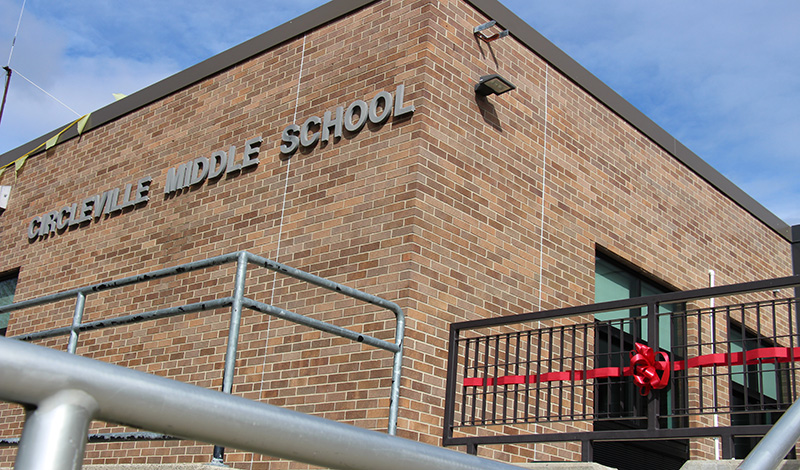 Brick building with the words Circleville Middle School on it. In front is a railing with a red ribbon and bow attacked.