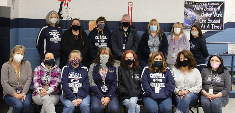 A group of 15 adults. Eight are sitting in front, with seven standing in back. They all have masks on.