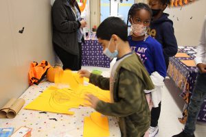 A boy and girl stand at a table and put together  a puzzle.