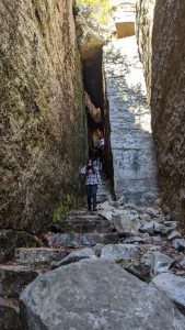 From below, you see a few high school students walking out of an area that was very narrow, large rocks.