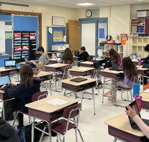 A classroom filled with students sitting at their desks.