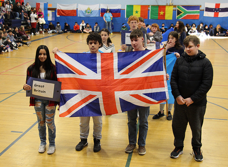 Four students stand together holding the flag for Great Britain. The girl on the left is holding a sign that says Great Britain.