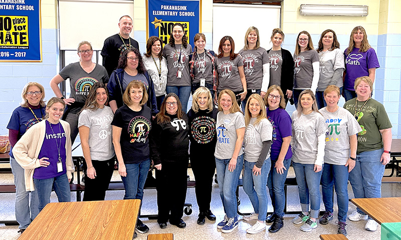 A group of 24 adult men and women in two rows, all wearing pi shirts.