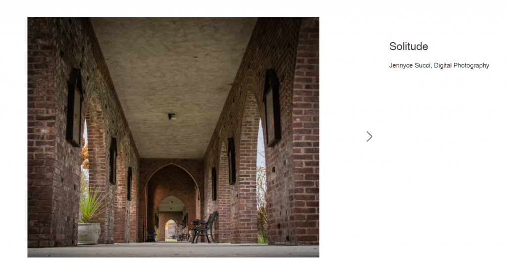 At ground level looking down a hall. The walls are red brick with windows.