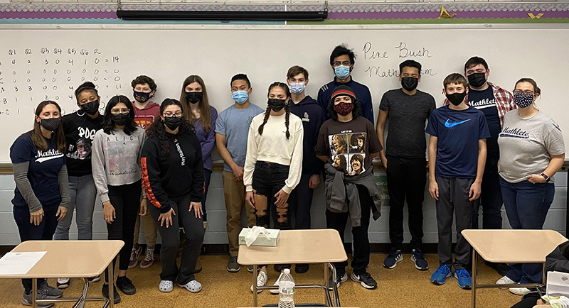 A group of 14 people, mostly high school students, stand together. They are all wearing masks.