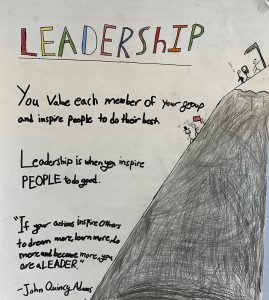 A poster that says Leadership at the top. There is a mountain drawn on the right with people climbing it.