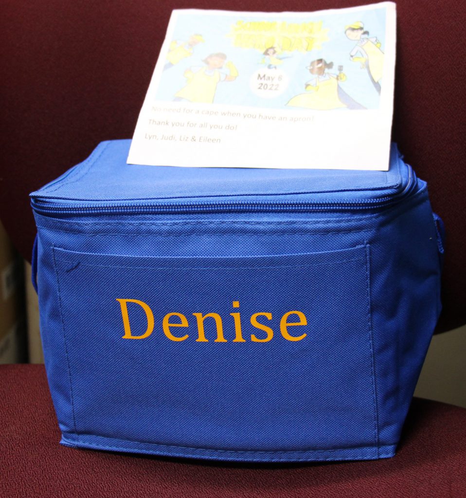 A blue lunch bag with the word Denise embroidered on it.