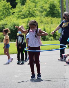 A girl with long braids has a hula hoop around her hips.