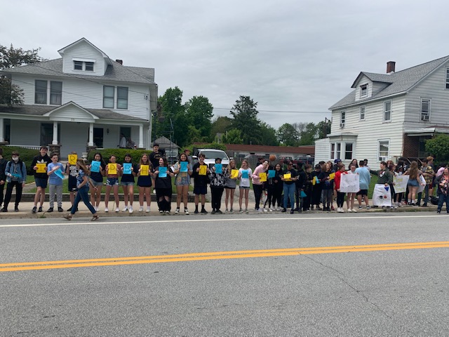 A group of middle school students stand in a line with signs.