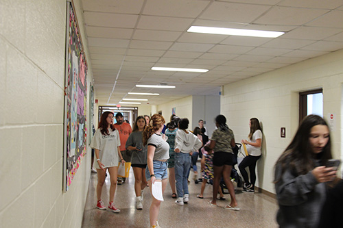 A group of adults and students in a school hallway.