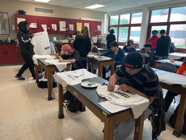 A class of high school students sitting at their tables making tshirts.