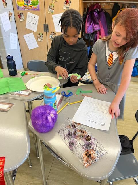 Two elementary age students work together building a science project.