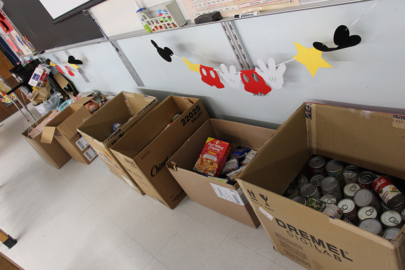 Several large brown cardboard boxes sit on a floor. They all have lots of food in them.