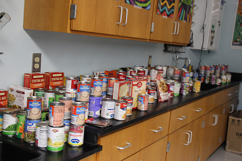 A counter in a classroom filled with cans and boxes of food.