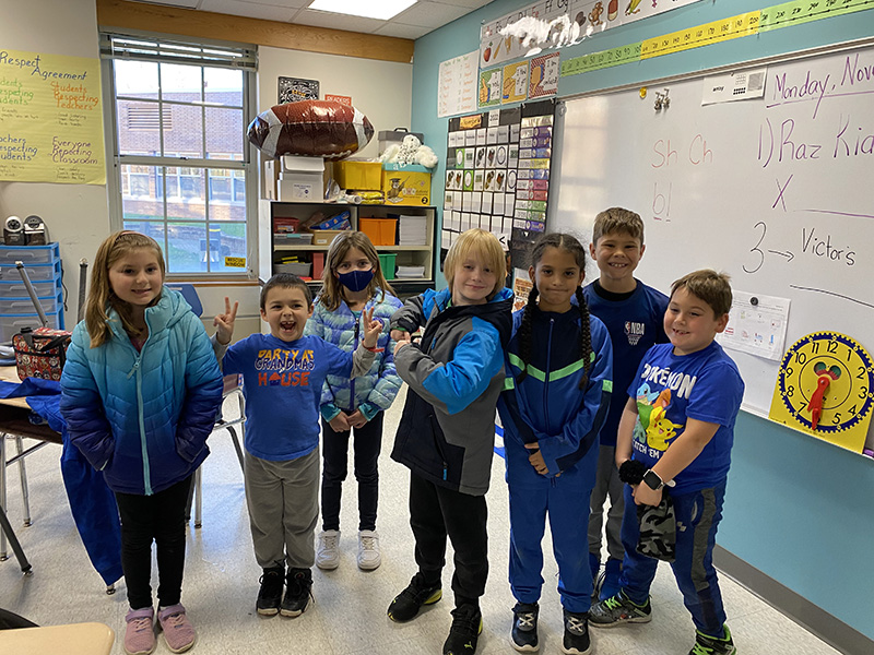 A group of seven  younger elementary  students all dressed in blue.