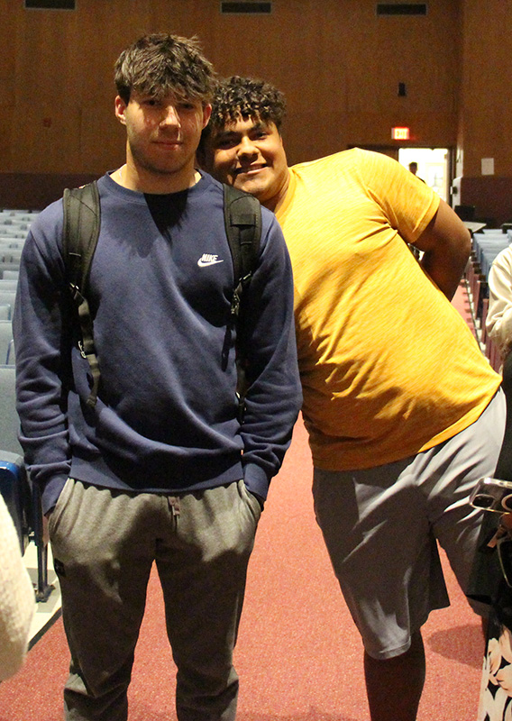 Two high school young men stand together and smile.