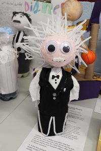 A soda bottle decorated to look like Albert Einstein with white pipe cleaners sticking up for his hair.