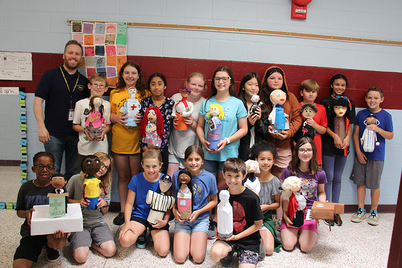 A large group of fifth-grade students holding their decorated soda bottles.