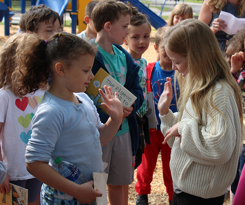 Two first grade girls give each other high fives.