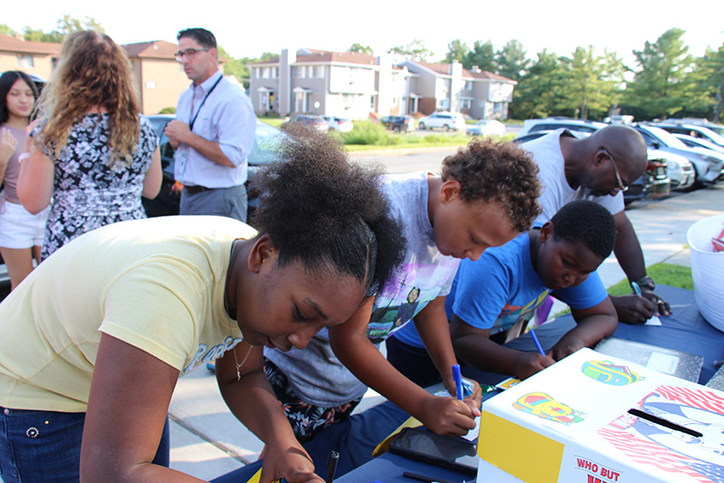 A group of four students lean over a table filling out raffle tickets.