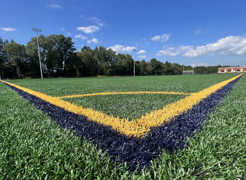 The view from the ground of a new synthetic field with gold and blue lines meeting to form a v in the corner.