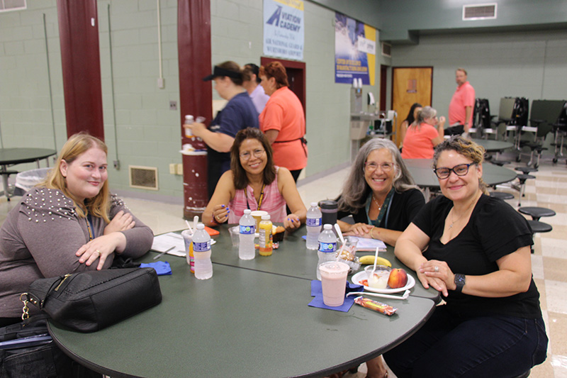 A group of four women sit at a round table eating breakfast.