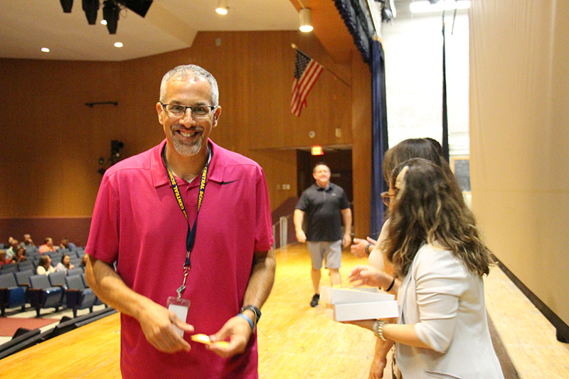 A man with gray hair smiles broadly as he walks past a group of people who just congratulated him.