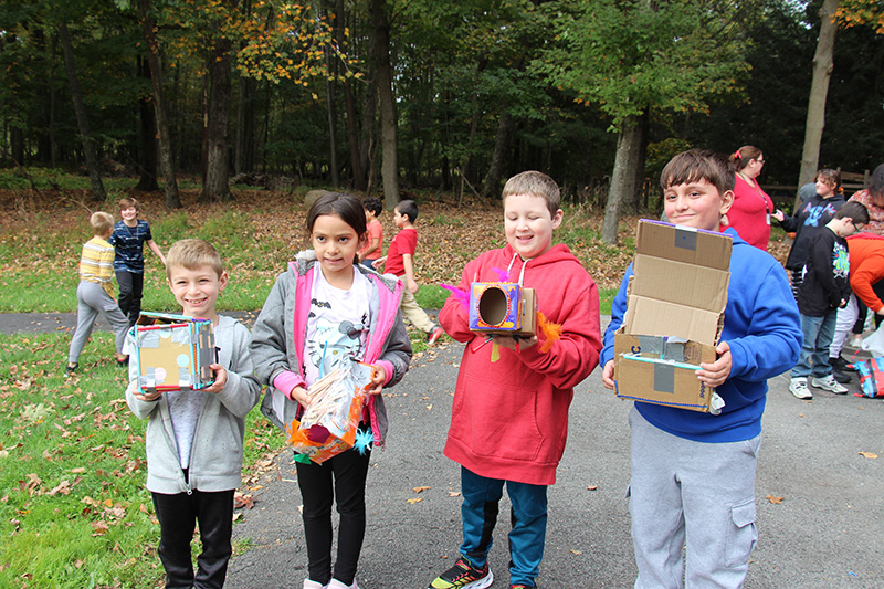 Four fourth-grade student smile as they hold boxes.