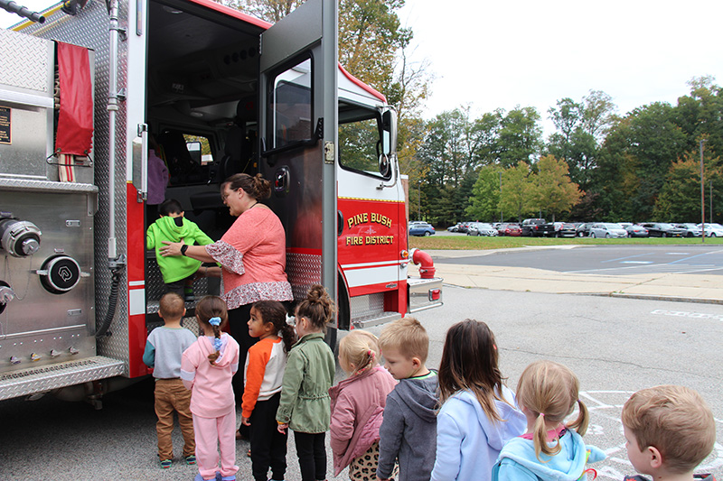 Small elementary students line up to get into a fire truck.