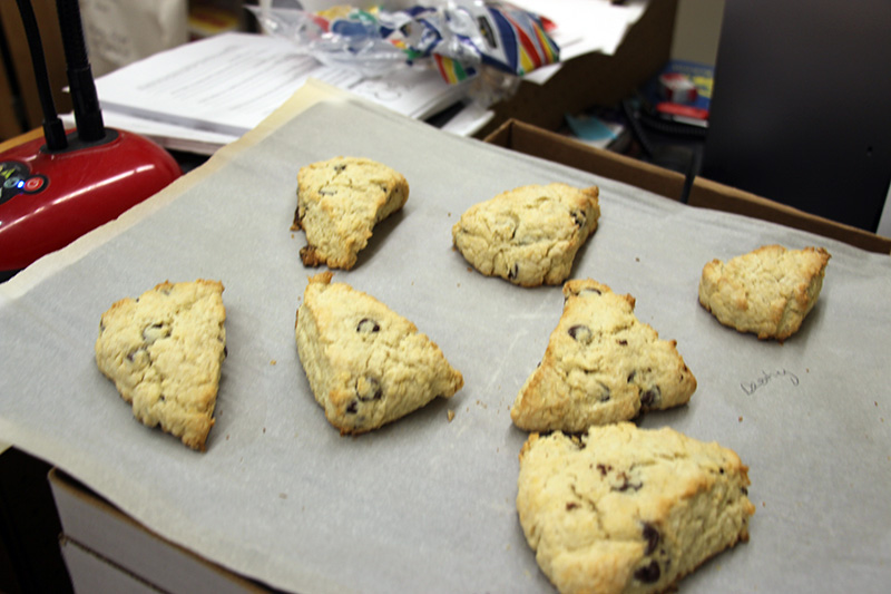 a baking sheet with seven baked scones on it.