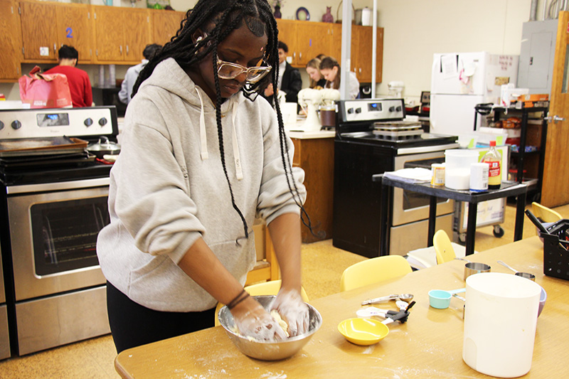 A high school girl mixes dough for scones.