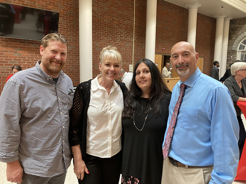 Four adults stand together smiling.