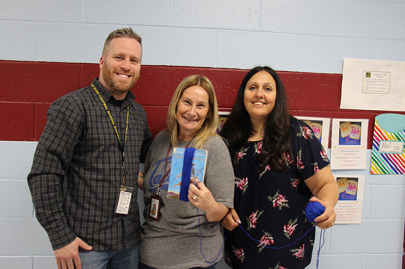 A man and two women stand smiling together. 