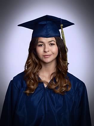 A young woman with long dark hair, wearing a navy blue graduation cap and gown.