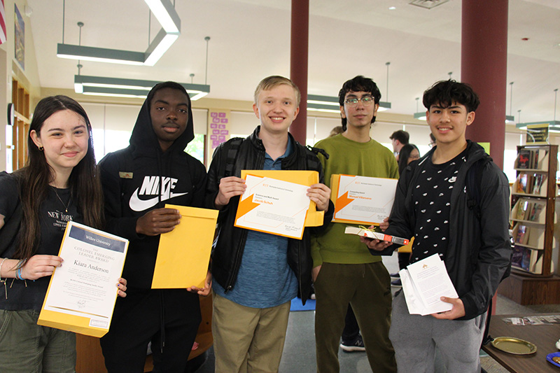 Five high school students smile. They are each holding manilla envelopes.