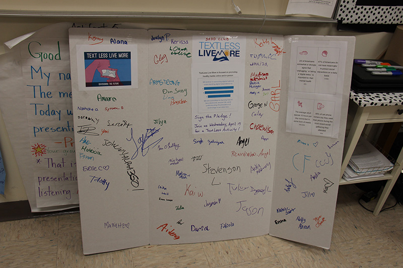 A white poster board with signatures on it in many different colors.