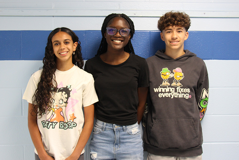 Two eighth-grade girls and one eighth-grade boy stand next to each other smiling.