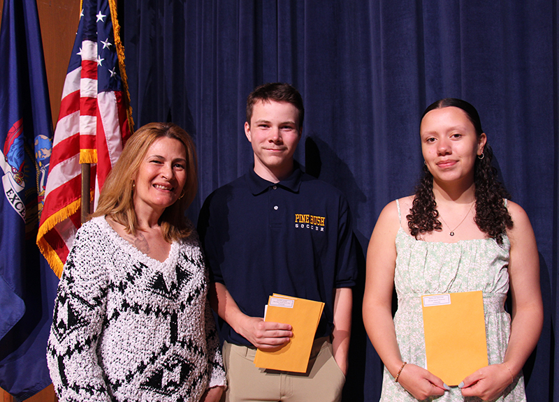 A woman on the left with two high school students, each holding manilla envelopes.