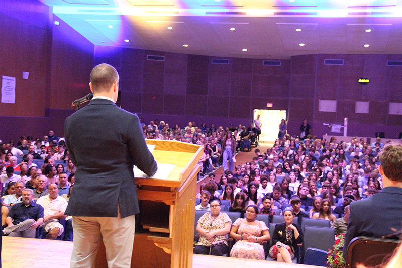 A man stands at a podium looking out at an auditorium filled with people.