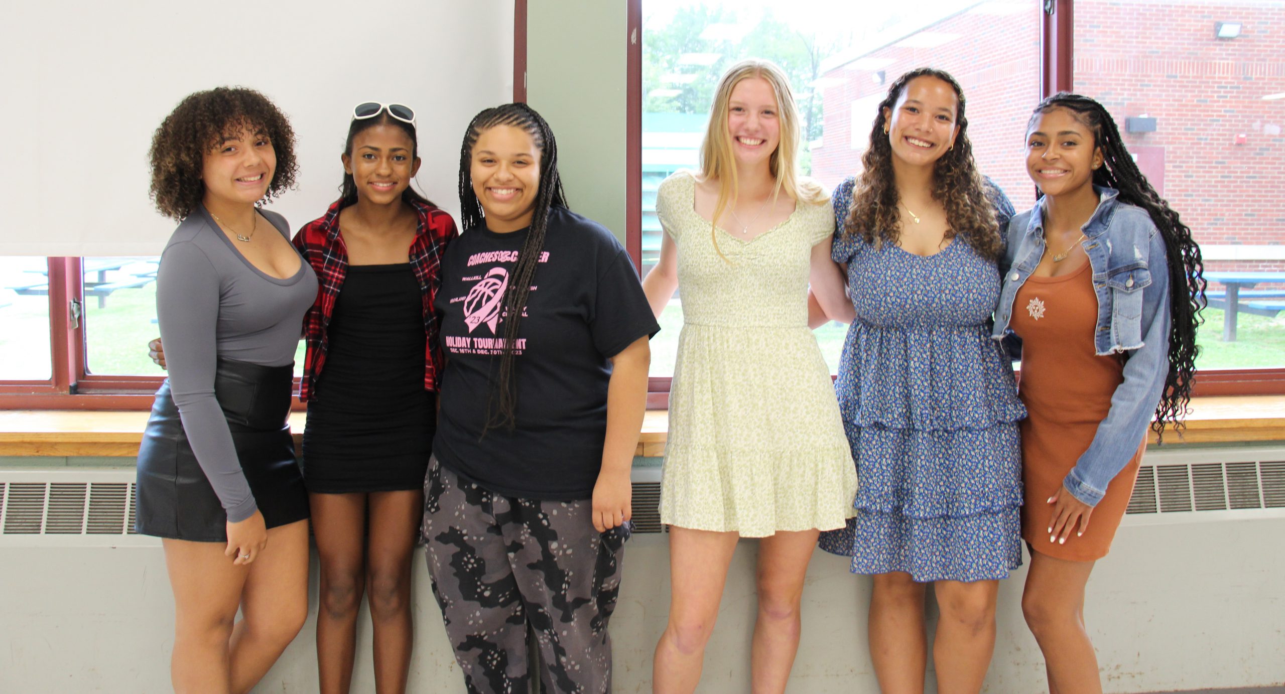 A group of six high school girls stand together smiling.