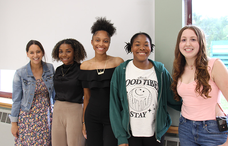 A group of five high schools girls stand together smiling.