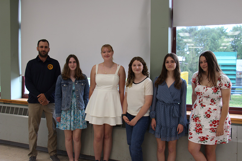 A man stands on the left. With him are five high school young women all smiling.