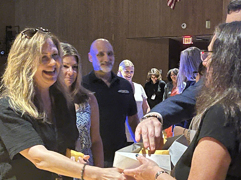 A line of people stand waiting to shake hands. The woman in front is smiling broadly.