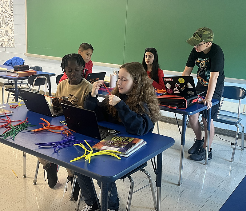 Sixth-grade students sit at desks working on their chromebooks.