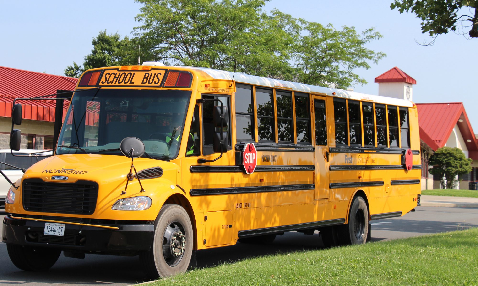 A large yellow school bus in front of a school building.