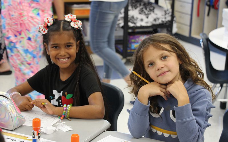 Three girls smiling as they arrive at Pakanasink Elementary School